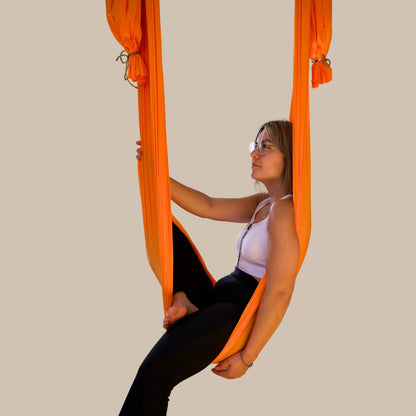 Aerial Yogatuch in lebhaftem Orange mit Affirmation auf gravierter Baumscheibe